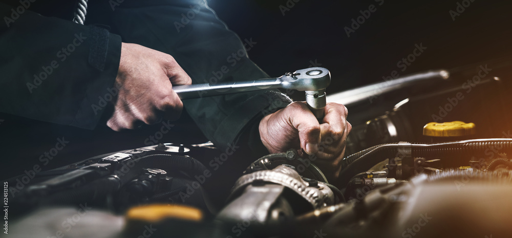Auto mechanic working on car engine in mechanics garage. Repair service. authentic close-up shot - obrazy, fototapety, plakaty 