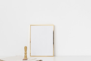 Gold a5 portrait frame mockup with gold stamp on white wall background. Empty frame, poster mock up for presentation design. Template frame for text, lettering, modern art.