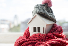House In Winter - Heating System Concept And Cold Snowy Weather With Model Of A House Wearing A Knitted Cap