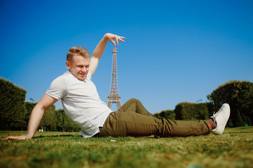 Tourist young man makes a photo against the background of the Eiffel Tower. Concept tourism.