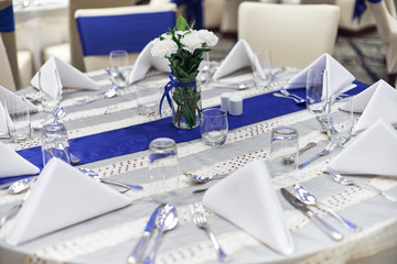 Wall Mural - Reception dinner table setup with dinnerware, napkin, spoon, fork and glasses decoration with blue sash cloth stripe