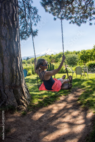 Fotografija Adult woman swinging on a wooden tree swing in Mt