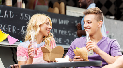 leisure and people concept - happy friends eating and talking at food truck