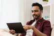 © Syda Productions - technology, leisure and people concept - happy man in earphones with tablet pc computer listening to music at home