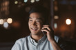 © mavoimages - Smiling Asian businessman talking on his cellphone at night