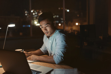 Young Asian businessman working online in a dark office