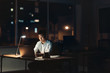 © mavoimages - Young Asian businessman working overtime in a dark office