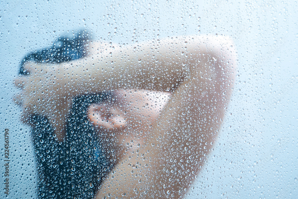 Women showering in the shower room close up with a water drop on glass door. - obrazy, fototapety, plakaty 