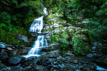 Poster - Beautiful waterfall falling from the high mountain. Midday scenery with blue sky.