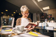 Picture of young smiling student girl sitting in book store and reading book. Drinking coffee and reading book.