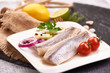Delicious Atlantic salted herring with onion and tomatoes on the slate shale background. Rustic style.
