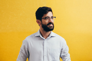 Emotion, portrait, businessman with a beard in glasses on a yellow background.