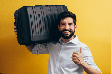 Sticker - Handsome young man holding a travel bag on his shoulder, isolated on yellow background