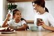Family. Eating. Home. Mom and daughter are talking and smiling while having lunch in the kitchen at home
