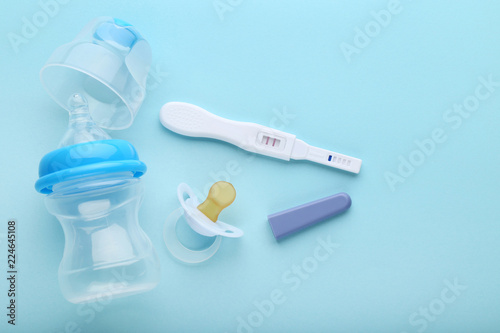 Pregnancy test with pacifier and little bottle on blue background Fototapeta