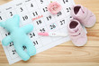 Pregnancy test with flower, soft toy and paper calendar on wooden table