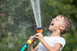 © altanaka - Happy little boy pouring water from a hose.