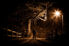 Night Stalker Concept. Man Standing On Wood Bridge Under Street Light In Dark Night