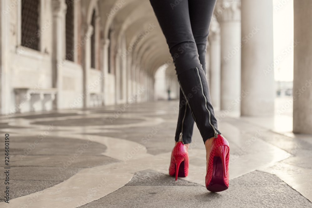 Woman walking in black pants and red high heels - obrazy, fototapety, plakaty 
