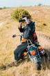 © LIGHTFIELD STUDIOS - young handsome man with binoculars sitting on vintage motorbike on rural meadow