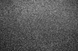 Dark gray background or texture of digital noise or grain of asphalt, graphite.