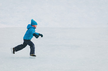 Canvas Print - little boy skating on ice in winter nature