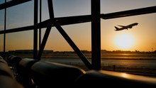 Silhouette Of An Airplane Taking Off At Sunset At Beijing Airport In The Background Of A Window.
