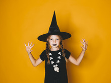 Young Halloween Witch On Orange Background With Black Hat