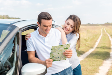 happy adult couple navigating with map while travelling by car