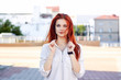 © Ирина Щукина - Red-haired teenage girl hold shirt collar with her hands. Natural ginger lady posing and looking at camera outdoors. Portrait of foxy beautiful caucasian woman.