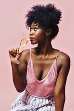 Close Up Of A Young Woman Sipping Champagne, Isolated On Pink