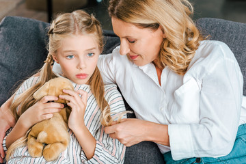 high angle view of mother and daughter sitting on couch together and chatting