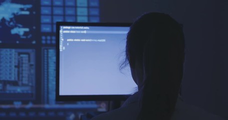 portrait of young woman hacker programmer working at a computer in the data center