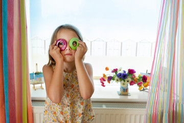 female child holding two colourful napkin rings up to her eyes