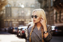 Outdoor Close Up Fashion Portrait Of Young Beautiful Woman Wearing Stylish Sunglasses, Wrist Watch, Gray Tartan Blazer. Model Looking Aside, Walking In Street Of European City. Copy Space For Text