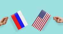 Flags Of Russia And The United States. The Hand Raises The Flag Of Russia And The USA. The Concept Of Relations Between States, Economic Community, Politics. Conflict Between The Great Powers.