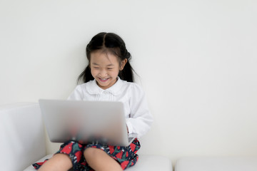 Little asian girl using laptop to studying. Education, free time, technology and internet concept.