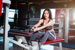 © Thinapob - Fitness Asian women performing doing exercises training with rowing machine (Seat Cable Rows Machine) in sport gym interior and fitness health club with sports exercise equipment Gym background.