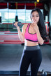 © Thinapob - Fitness Asian women performing doing exercises training with dumbbell sport in sport gym interior and fitness health club with sports exercise equipment Gym background.