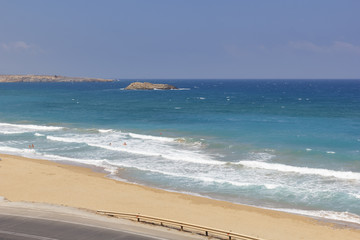 white splashes of waves in the sea rolling on the sandy shore