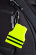Yellow pedestrian safety reflector on a black backpack, closeup view. Concept of safety