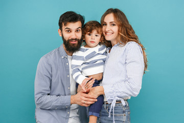 Wall Mural - A happy family on blue studio background. The father, mother and son posing together