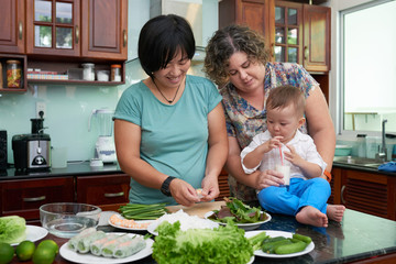 Cheerful homosexual couple cooking healthy breakfast for their son