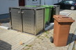 Stationäre Einhausung von Abfall-Sammelbehältern als Sichtschutz vor Wohnhäusern im Neubaugebiet