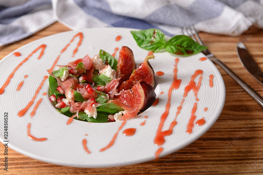 Plate with delicious fig salad and sauce on wooden table