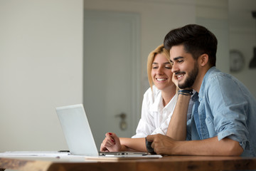 Photo of cheerful loving young couple using laptop