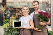© LIGHTFIELD STUDIOS - happy florists holding tablet with blank screen and burgundy roses near flower shop