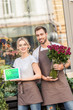 © LIGHTFIELD STUDIOS - smiling florists holding tablet with shopping appliance and burgundy roses near flower shop