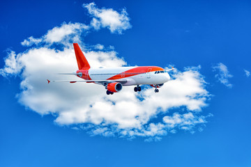 Red and white aeroplane in blue cloudy sky.