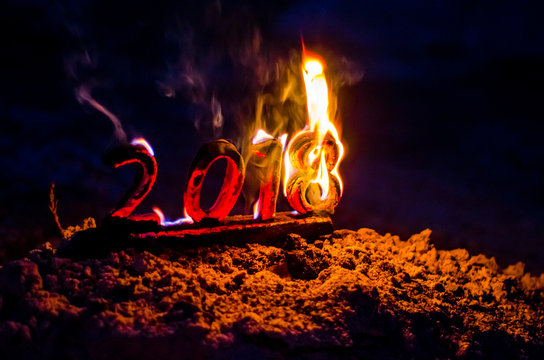 Wooden figures 2018 are burned in a flame. Conceptual photo end of the year.